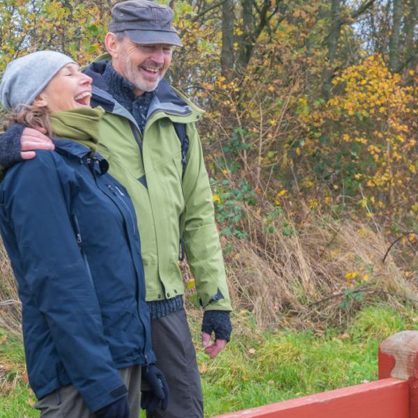 Efterårsbillede af grinende par på vandretur ved Trebjerg på Sydfyn