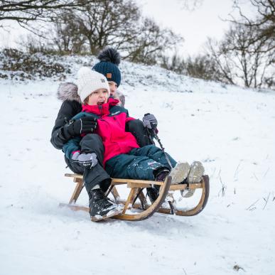 To børn kælker i sneen