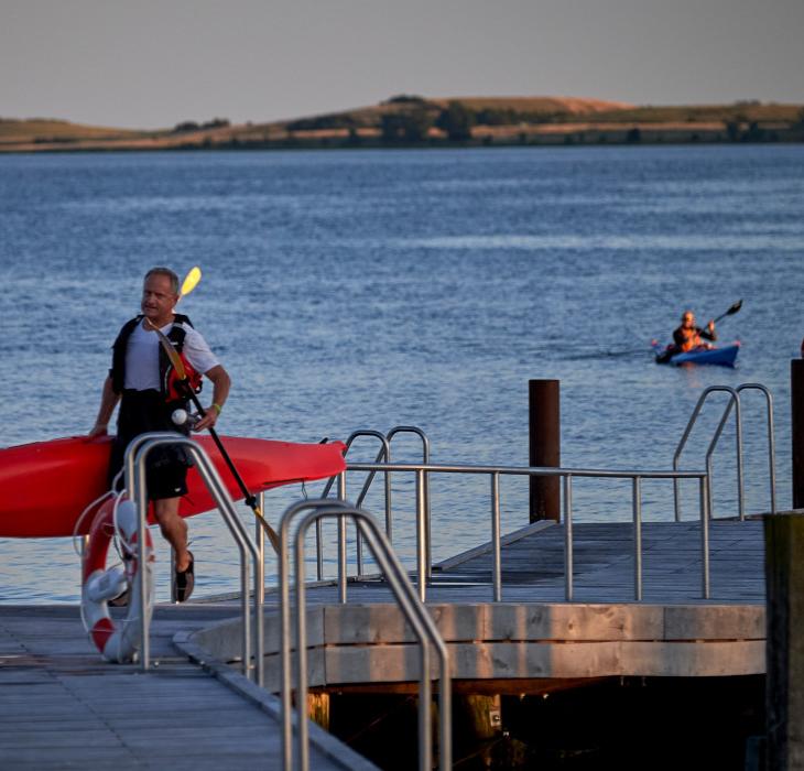 Feriegæst bærer en kajak på Faaborg Havnebad